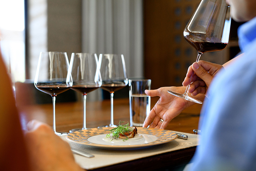 profile photo of man enjoying a tasting dish with four glasses of red wine on the table in front of him