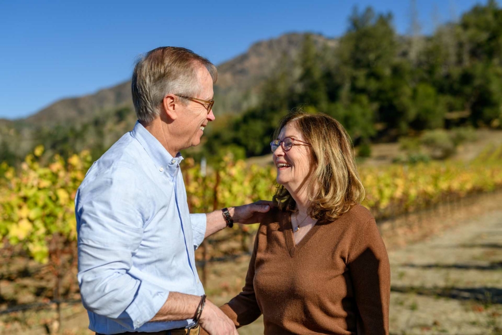 George Hamel Jr and Pam Hamel smiling at one another. Photo taken in the Hamel vines.
